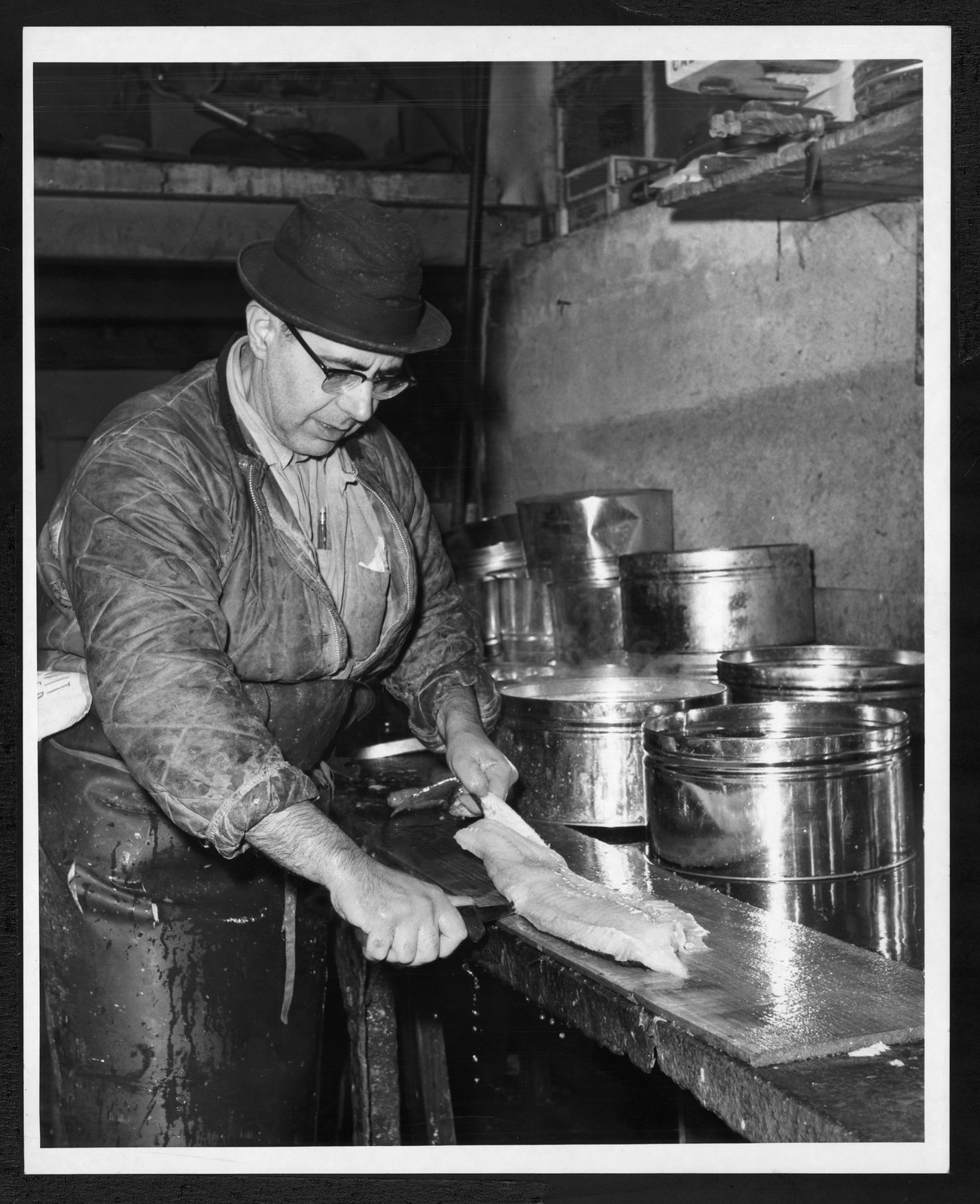 Man filleting fish at a market counter — historic image