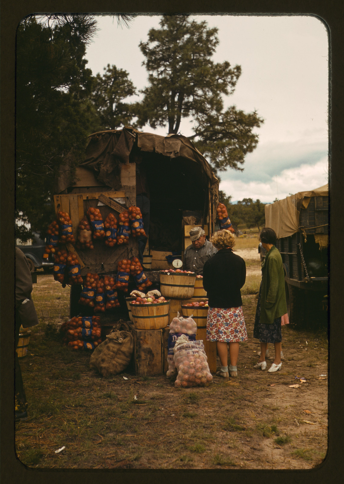 Fruit wagon with oranges and potato sacks at an outdoor market — historic image