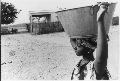 [Sahelian zone of West Africa, 1973: woman carrying large metal container on head]
