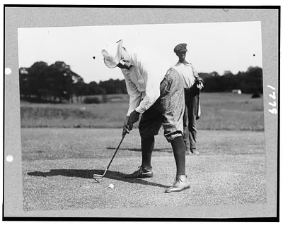 [Warren G. Harding bending over to hit golf ball, possibly in Washington, D.C.]