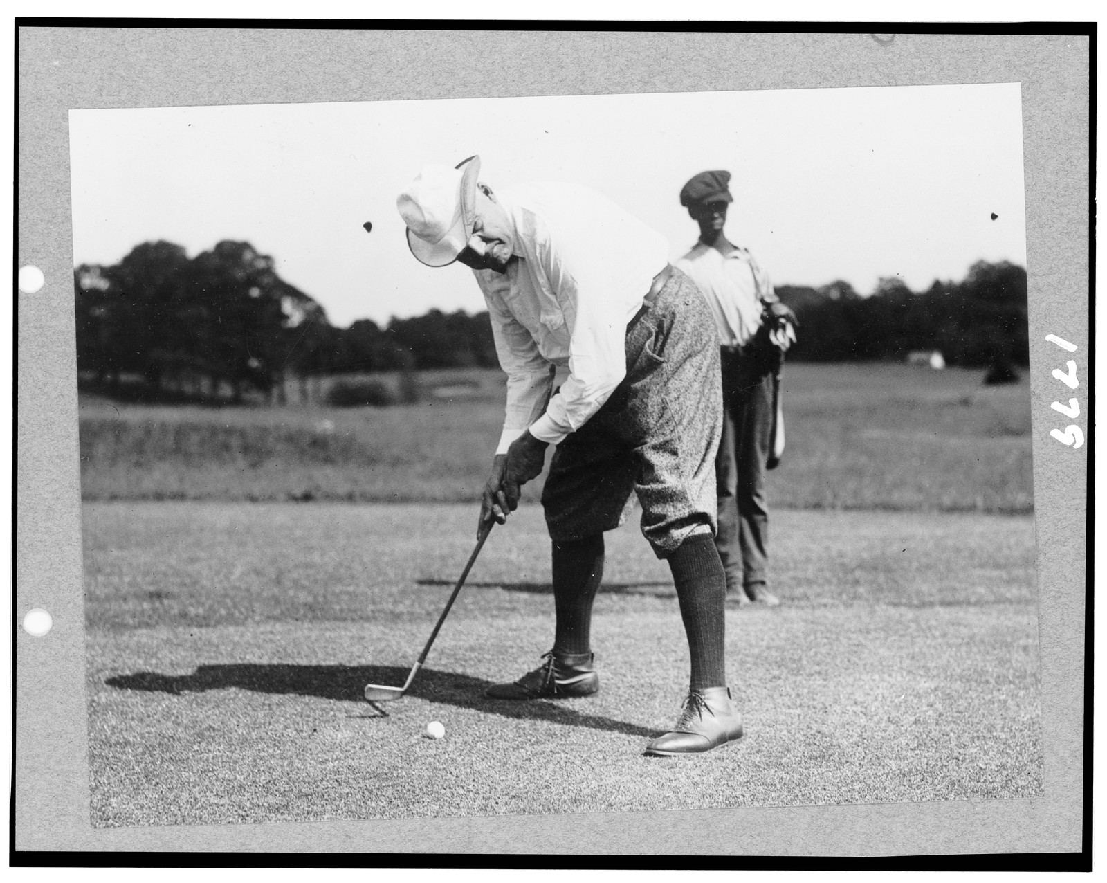 [Warren G. Harding bending over to hit golf ball, possibly in Washington, D.C.], [between 1921 and 1923?] — historic photograph