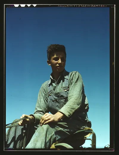 Portrait of a farm boy in overalls on farm machinery