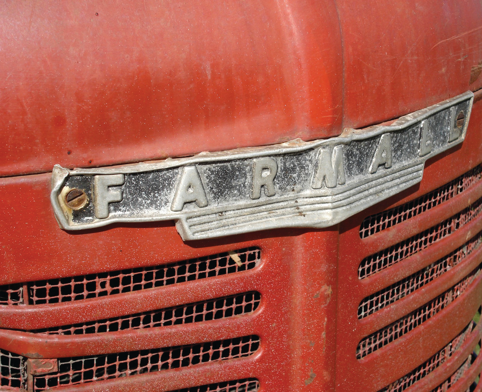 Close-up of red Farmall tractor hood emblem — historic image