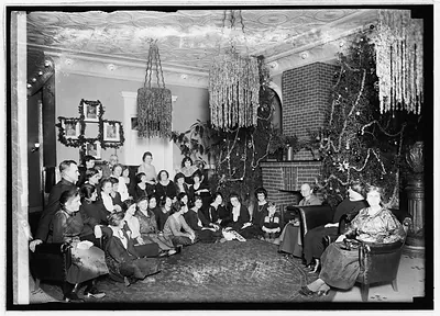 Women gathered around a decorated Christmas tree in a parlor