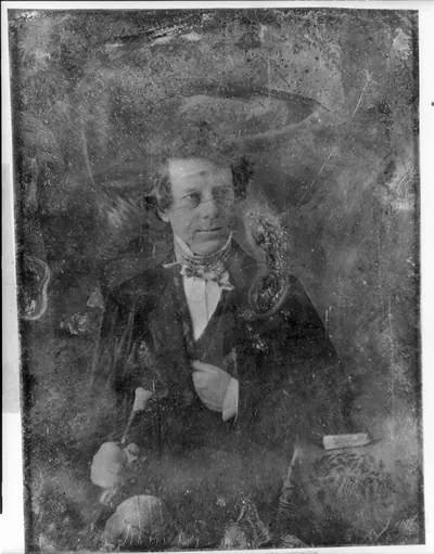 [Henry Inman with walking stick, half-length portrait, facing three-quarters to the right, seated, with a book on a small table covered with a tablecloth showing lyre ornament]