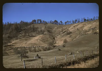 Hillside farm landscape with fences and a seated figure
