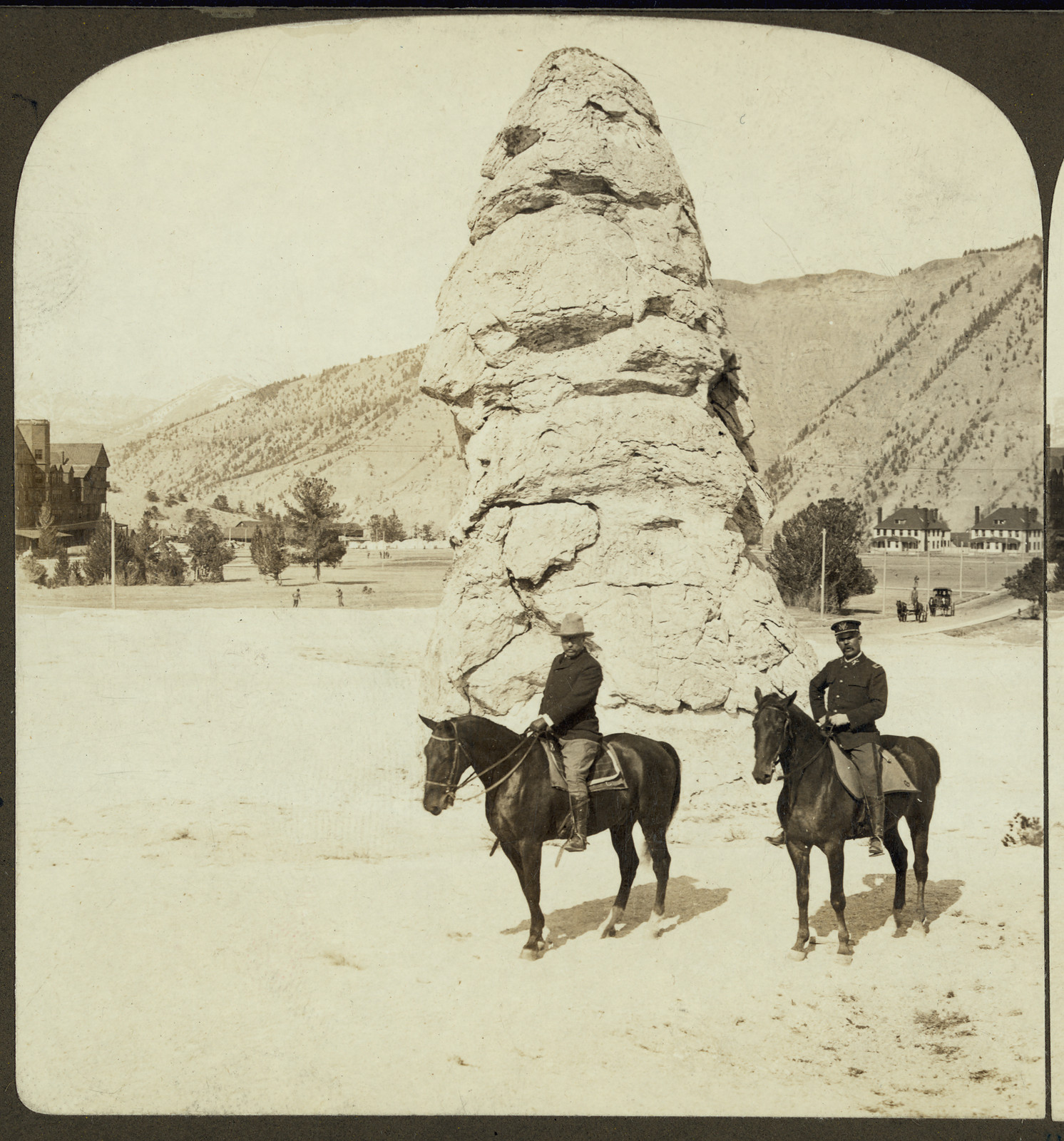 Two horsemen beside a tall rock pinnacle, Yellowstone — historic image