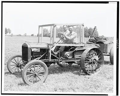 [W.O. Young seated on tractor, with screen built around his seat for protection against golf balls, on the Lincoln Park Golf Course, Chicago, Illinois]