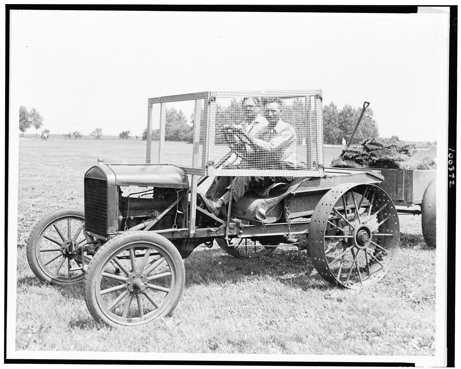 [W.O. Young seated on tractor, with screen built around his seat for protection against golf balls, on the Lincoln Park Golf Course, Chicago, Illinois], 1930 June 23. — historic photograph