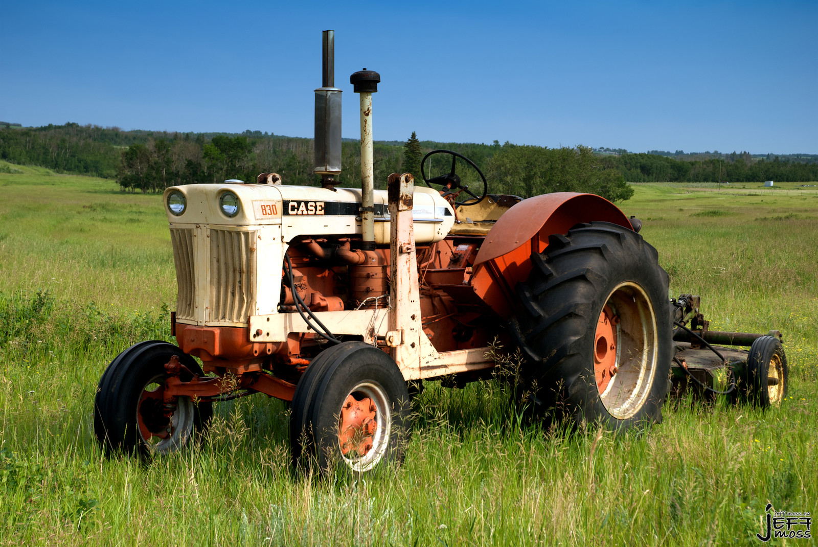 Abandoned Case 830 tractor in a grassy field — historic image