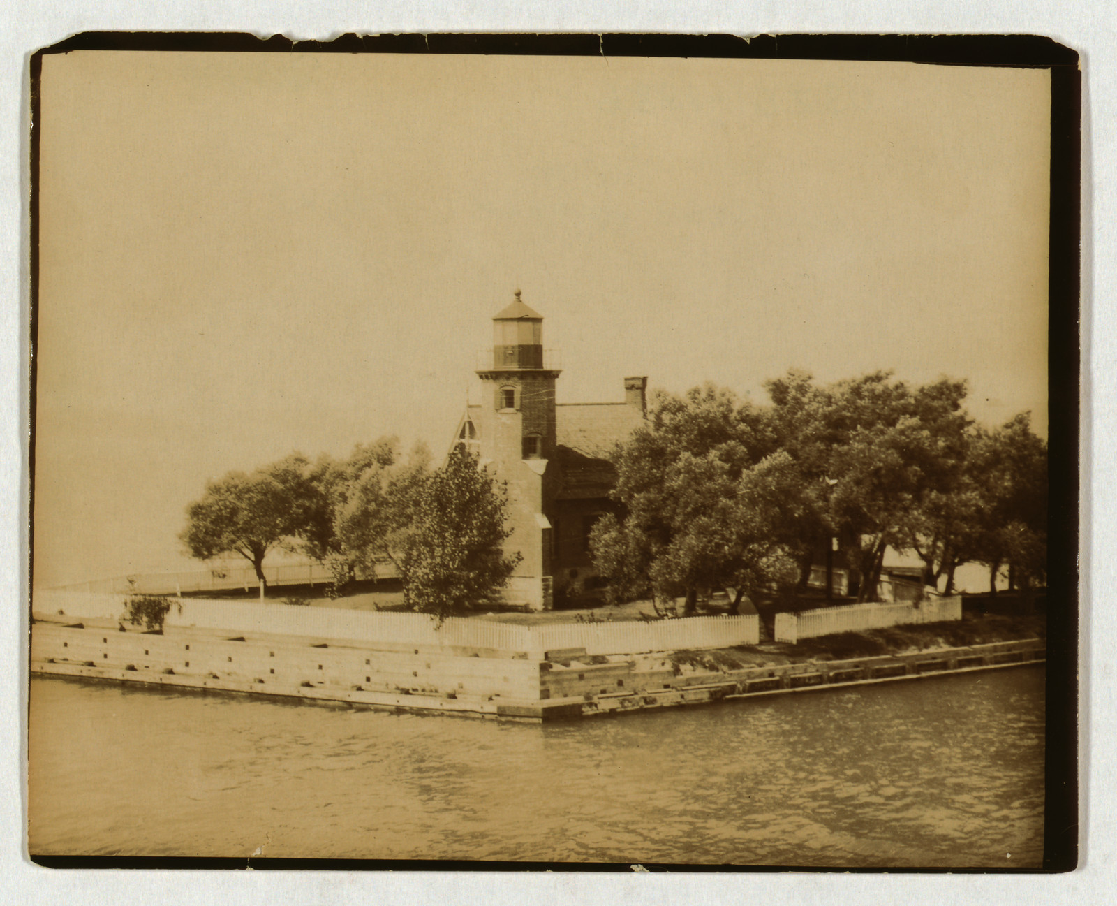 Lighthouse on a stone pier among trees, sepia photograph — historic photograph
