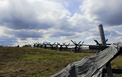 Split-rail zigzag fence across grassy field under cloudy sky