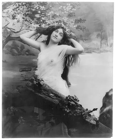 [Young woman modeling: nude with garland of flowers]