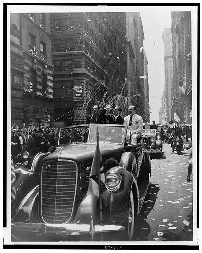 [Grover Whalen (left) seated on back of open car, with Howard Hughes (waving) and Albert I. Lodwick during a ticker tape parade up Broadway, New York City]