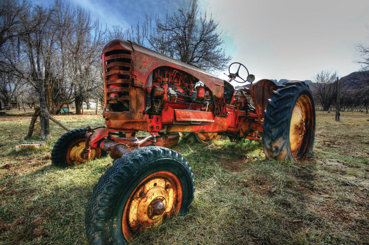 Rusty red vintage tractor in a dry field — historic image