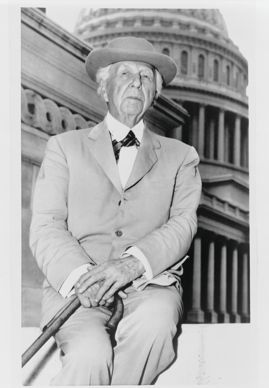 [Frank Lloyd Wright, three-quarter length portrait, seated, facing front, outside the U.S. Capitol building] — historic photograph