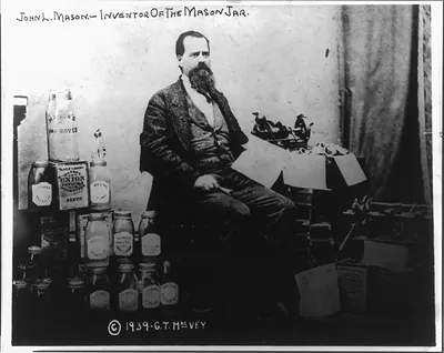 [John Landis Mason, full-length portrait, seated, facing right, alongside stack of Mason jars]