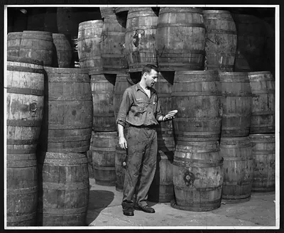 Man in work clothes among stacked wooden barrels