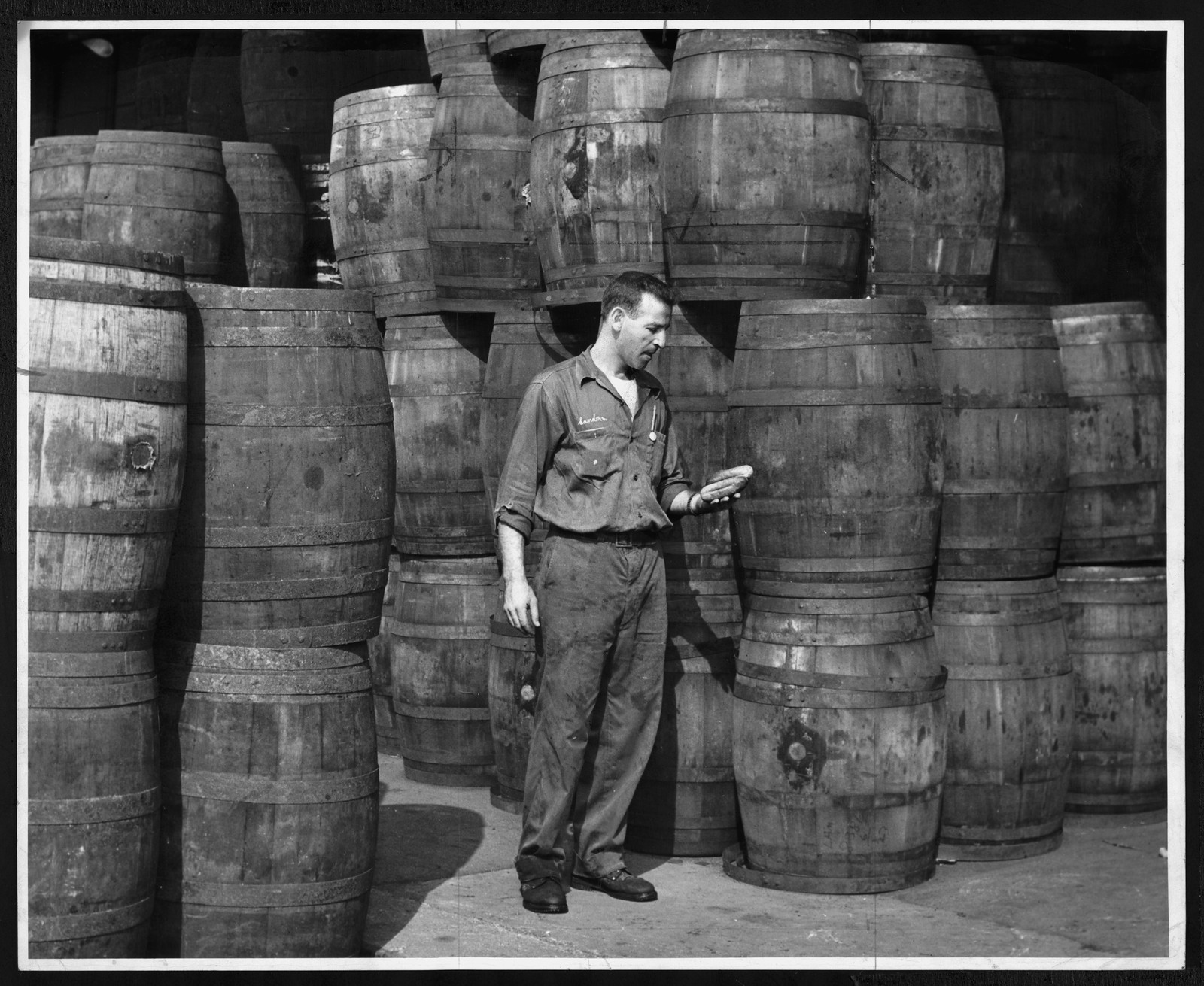 Man in work clothes among stacked wooden barrels — historic image