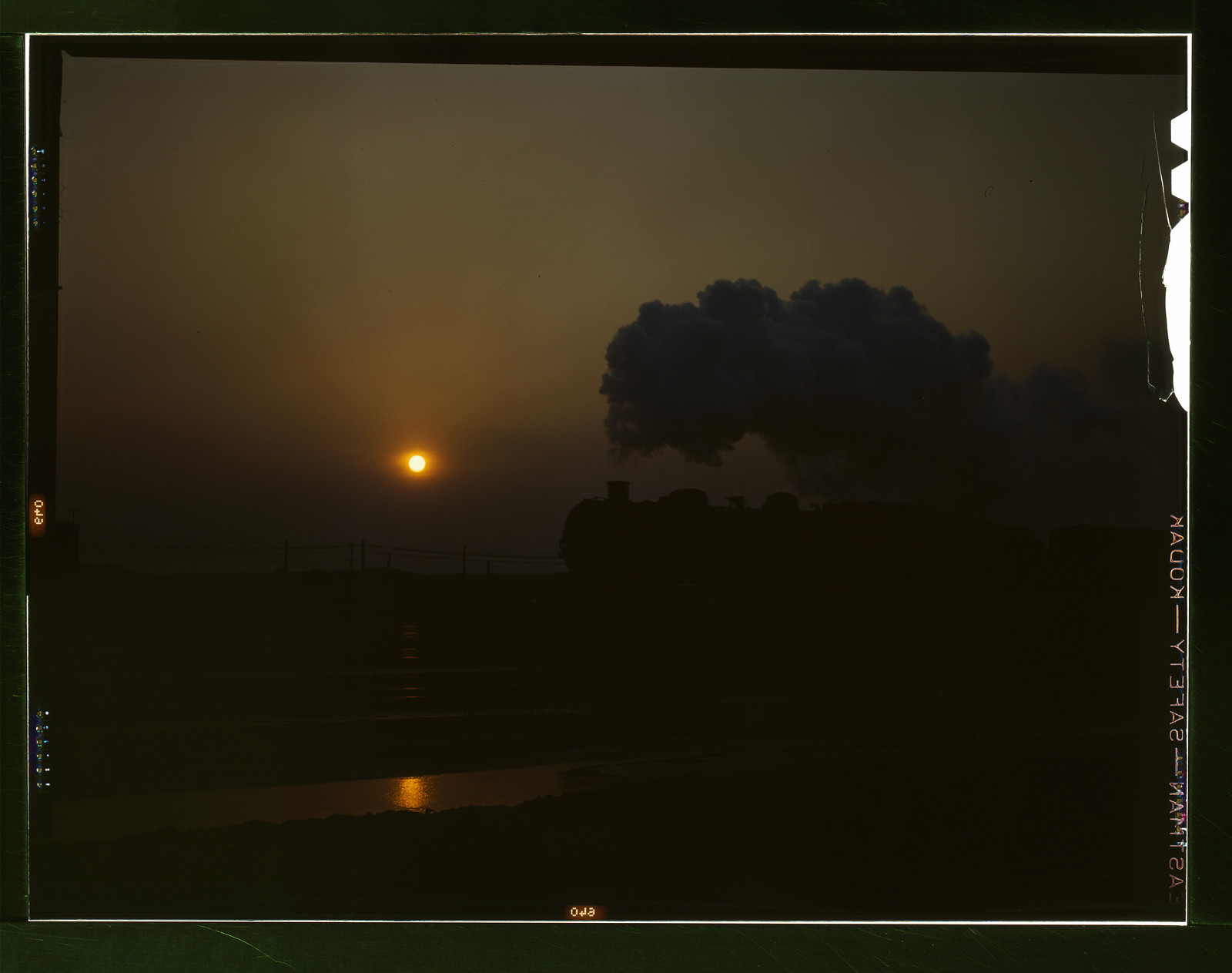 Steam locomotive silhouetted at sunset with smoke plume — historic image