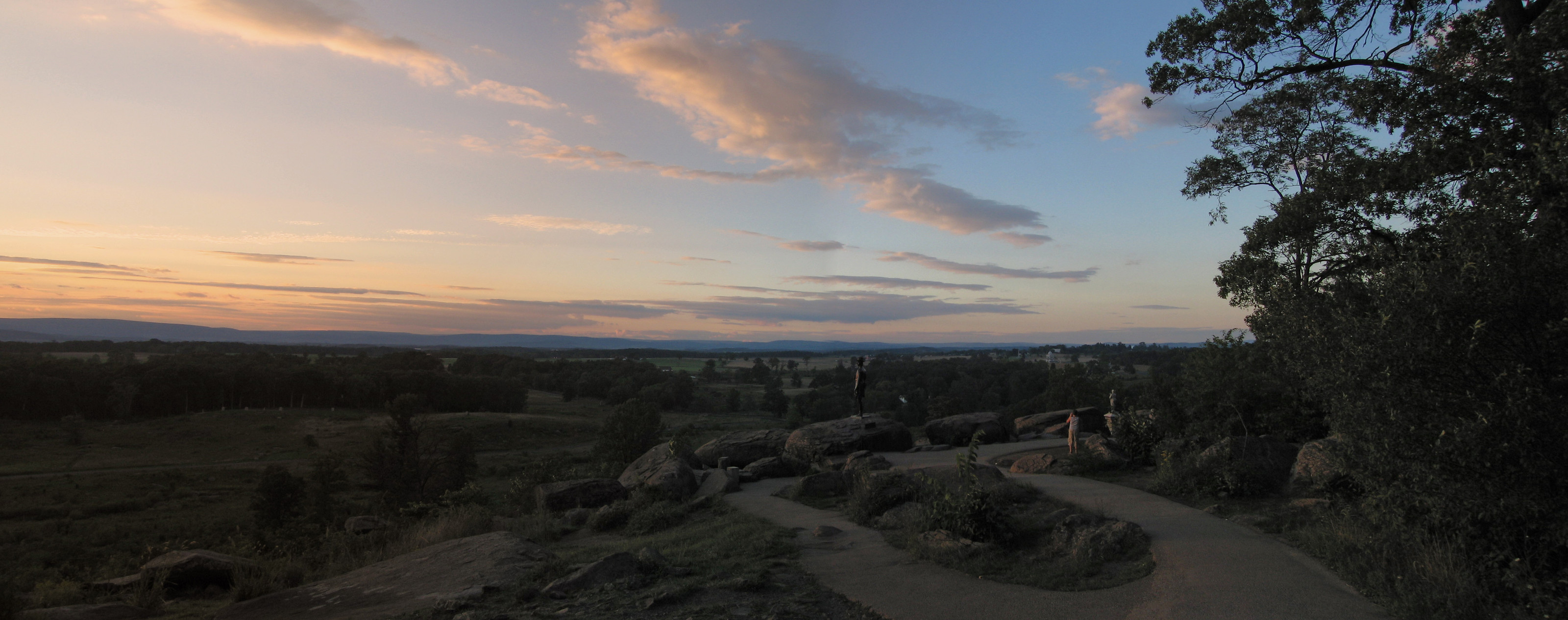 Sunset over a rolling landscape with rocks and a winding path — historic image