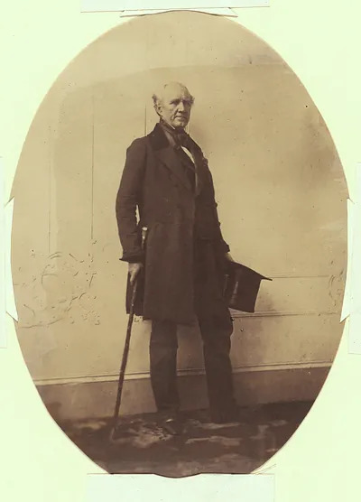 Elderly man in frock coat with cane and top hat