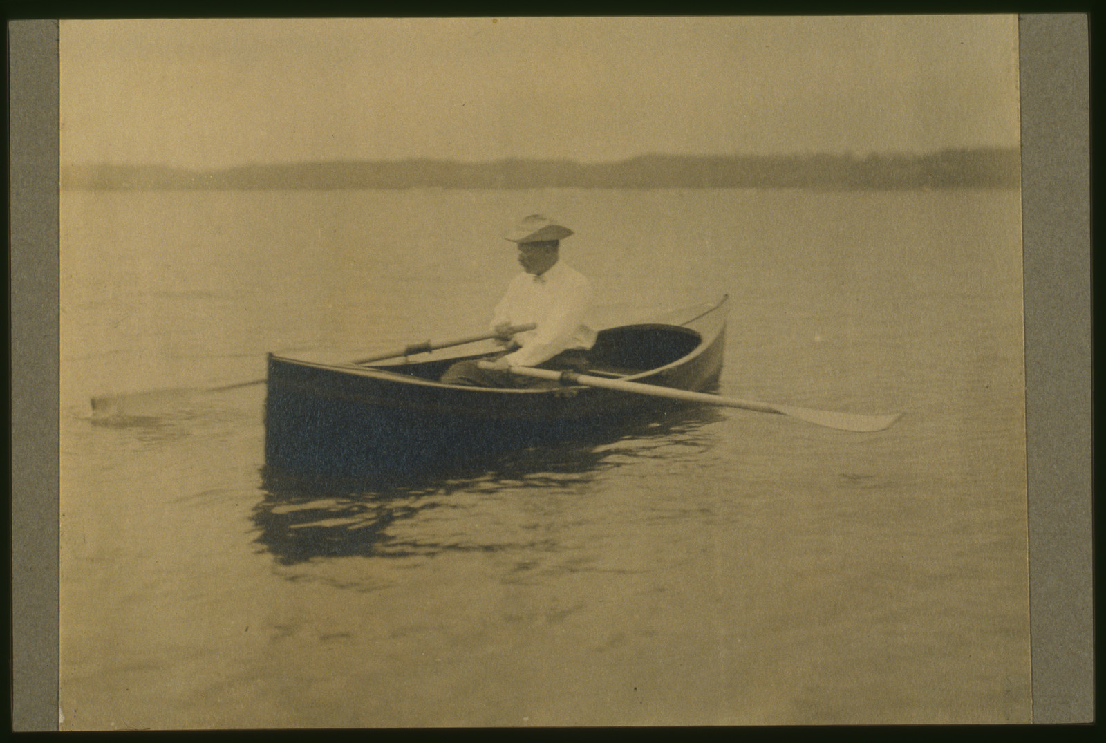 [Theodore Roosevelt, seated in rowboat, rowing], c1905. — historic photograph