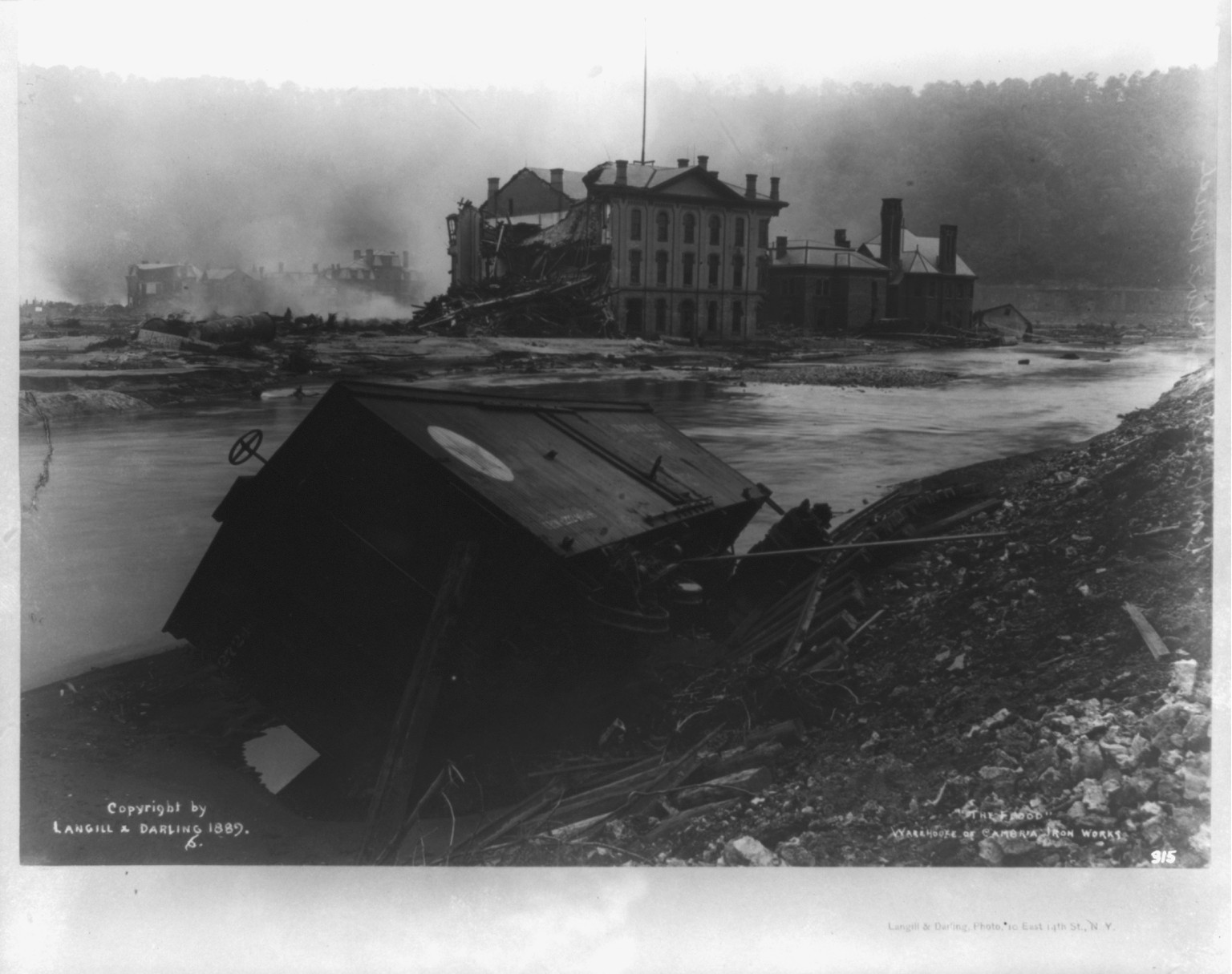 The flood, Johnstown, Pa., showing debris, warehouse of Cambria Iron Works, c1889. — historic photograph