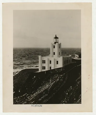 White Art Deco lighthouse on a cliff above the sea