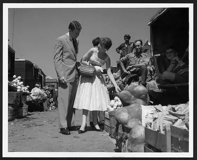 Couple shopping at an outdoor market with melons