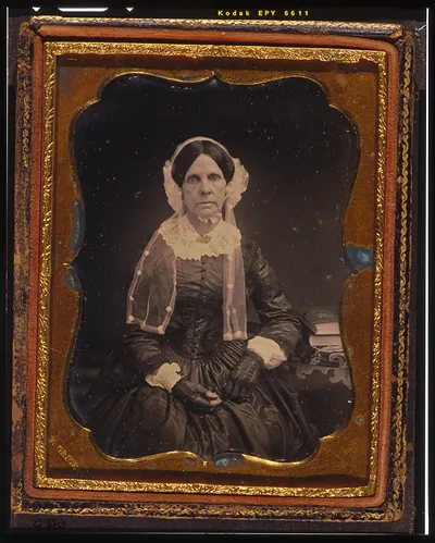 [Unidentified woman, three-quarters length portrait, seated with left arm resting on table with tablecloth and book]