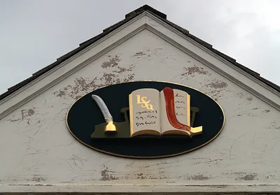 Quill and open book plaque on a gabled building