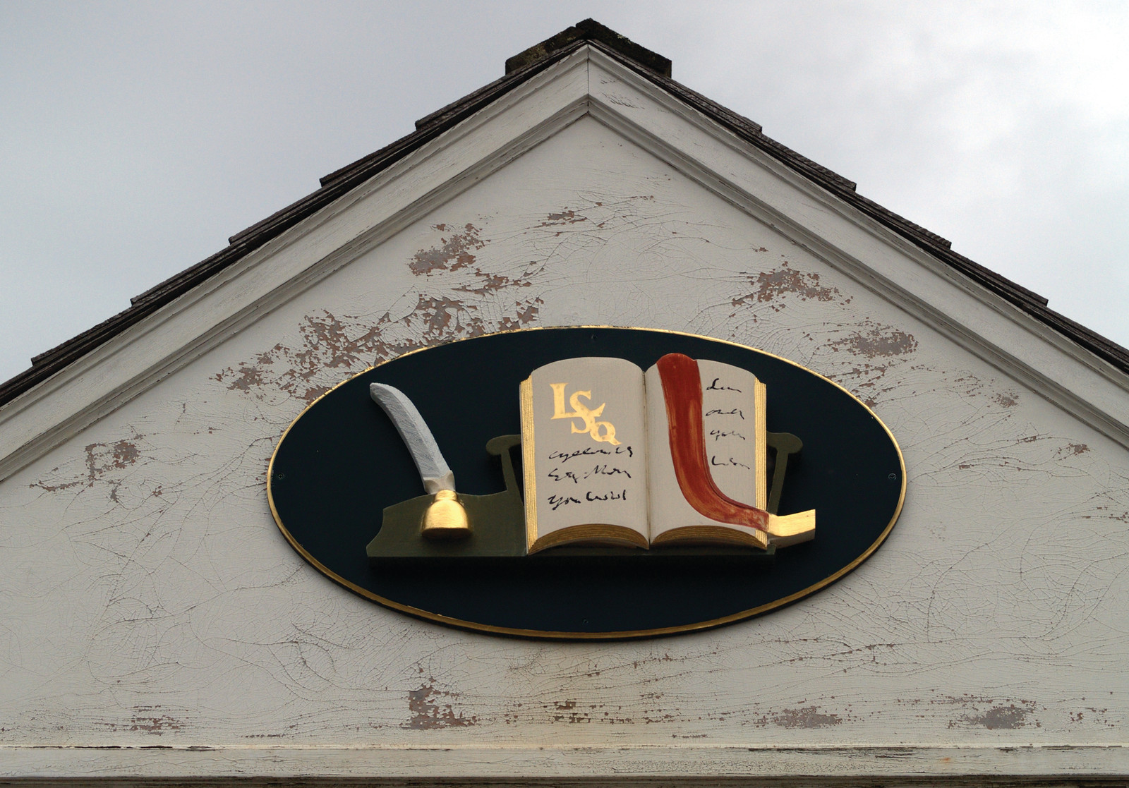 Quill and open book plaque on a gabled building — historic image