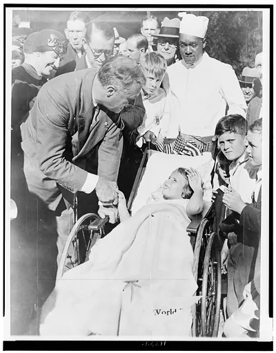 [Franklin D. Roosevelt, governor of New York, greets girl in wheelchair]