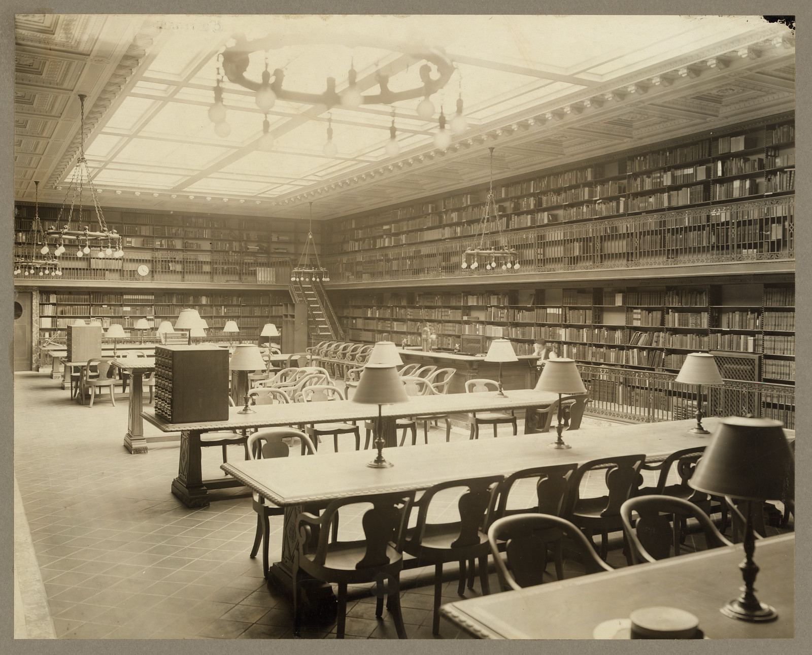 Circulating department reading room with bookshelves and lamps — historic image