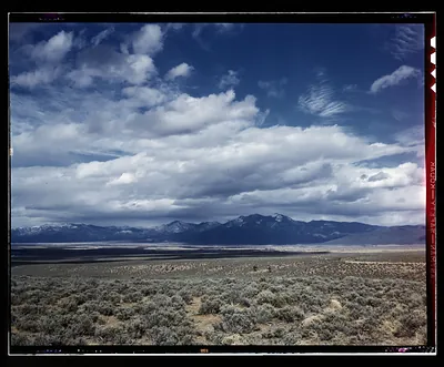 Snow-dusted mountain range over sagebrush plain under clouds