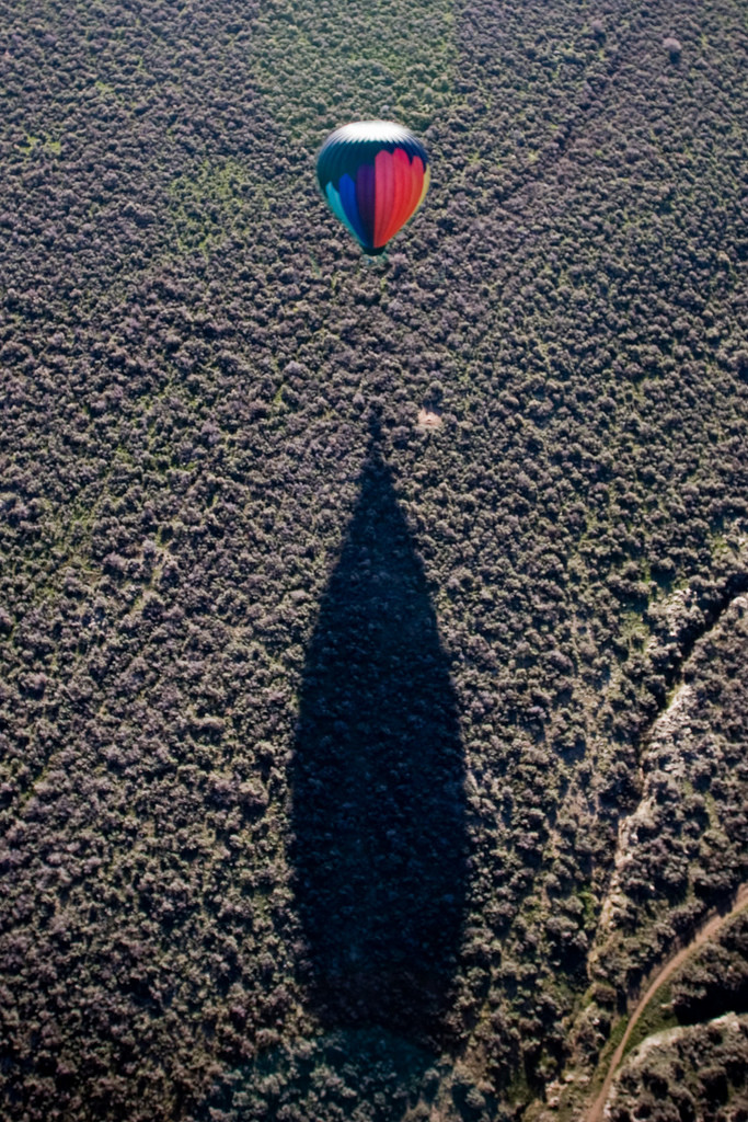 Hot air balloon casting a long shadow over trees — historic image