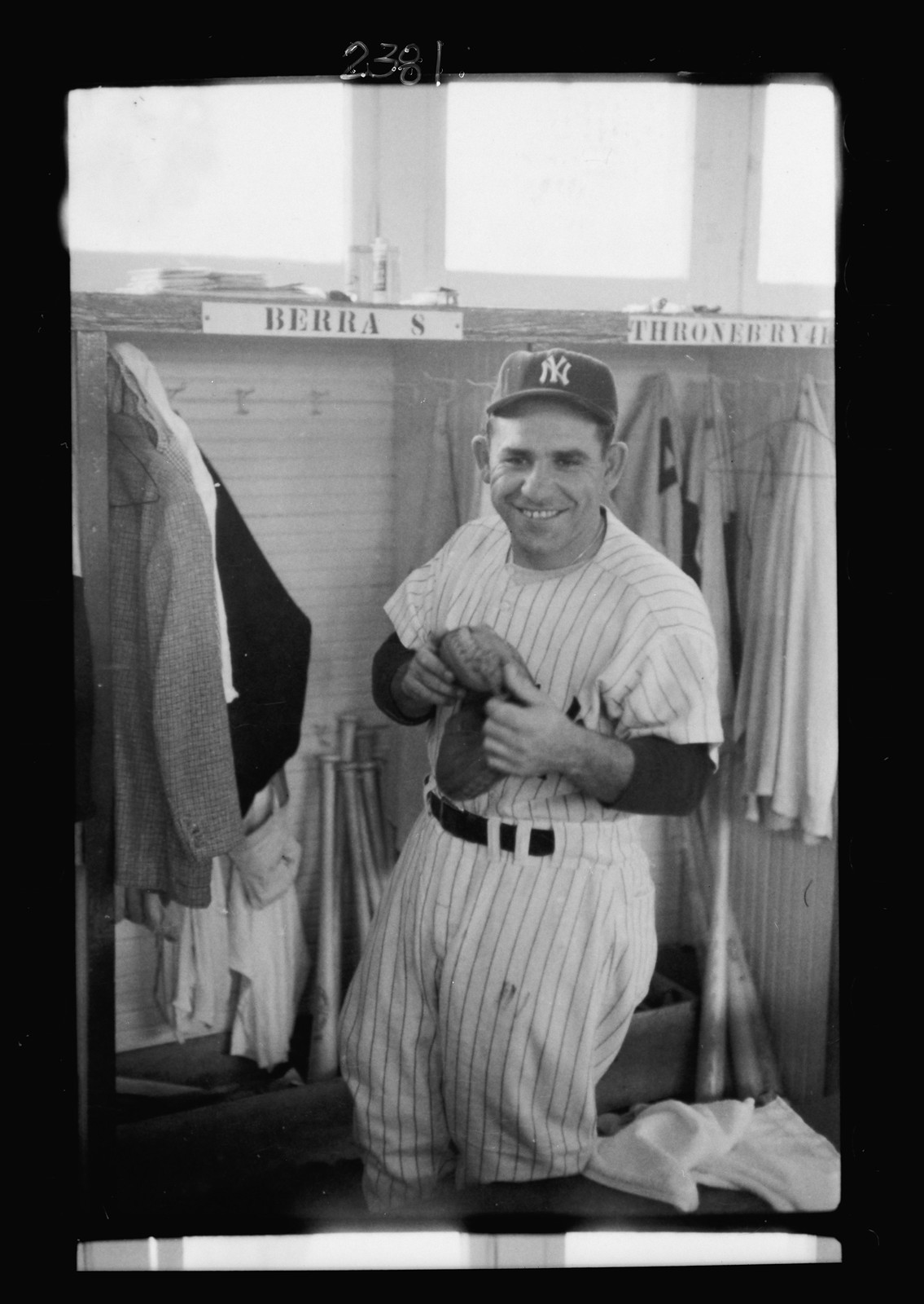 [New York Yankee baseball player Yogi Berra, three-quarter length portrait, in uniform, in the locker room] / Marvin E. Newman. — historic photograph