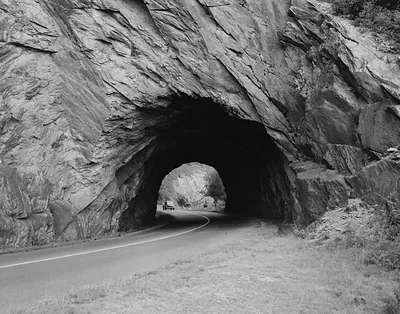 Rock tunnel through cliff on a curving road
