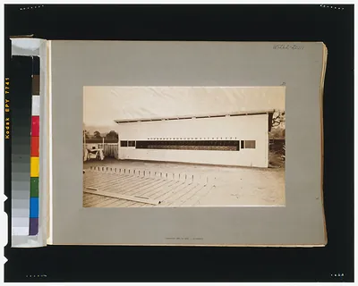 Photograph of a long white building with a sloped roof