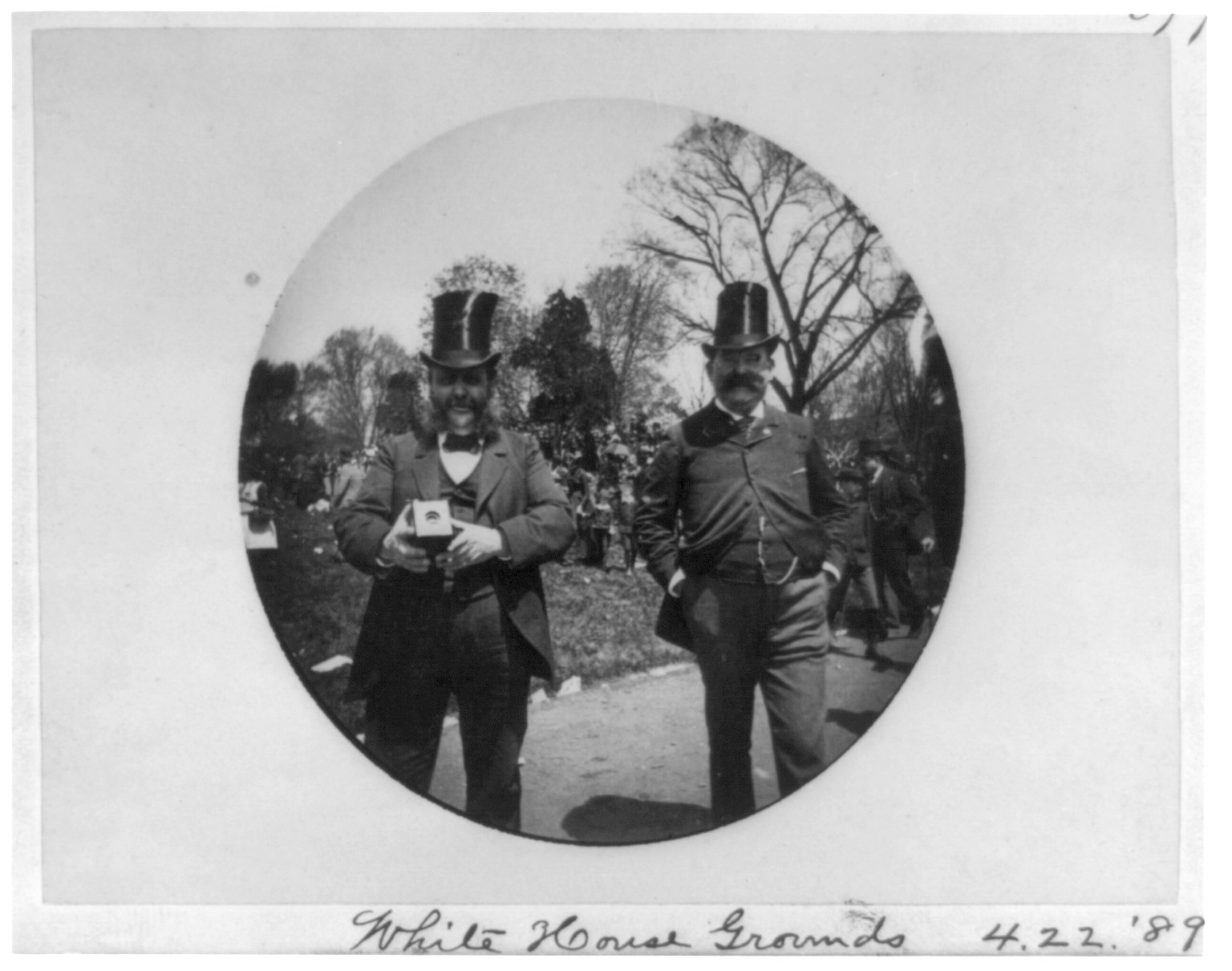 2 men in high silk hats, one with camera, on the White House grounds, Washington, D.C., [between 1900 and 1935(?)] — historic photograph