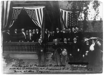 [President Roosevelt and his detectives at Sagamore Hill, Oyster Bay, L.I., posed on porch with flags]