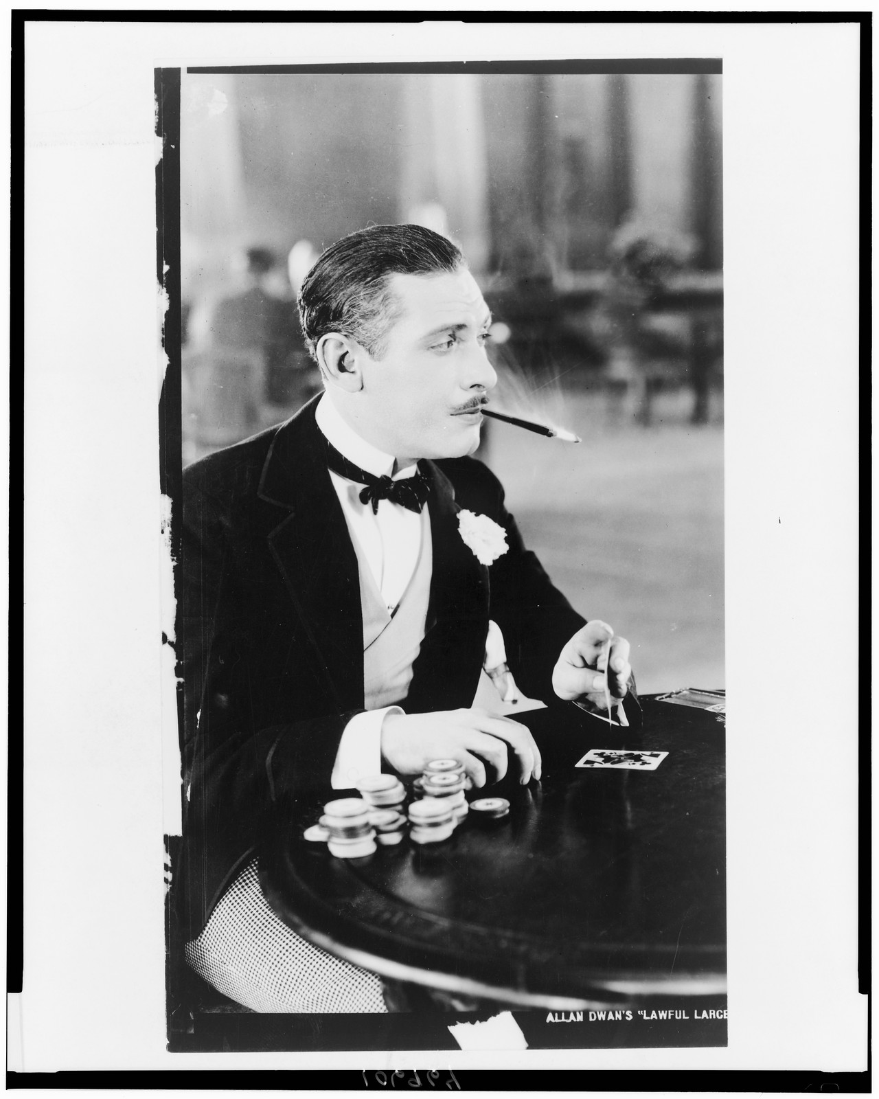 [Man, with cigarette holder in mouth, playing cards], [1930] — historic photograph