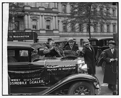 Men with Thanksgiving turkeys on Oldsmobile car, Minnesota to Washington banner