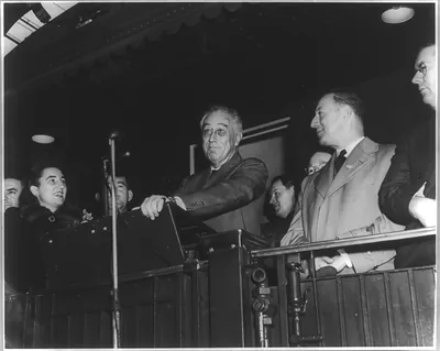 [Franklin Delano Roosevelt, Pres. U.S.; half-length, standing facing slightly left; with others on train; speaking during campaign at Bridgeport, Conn. ]