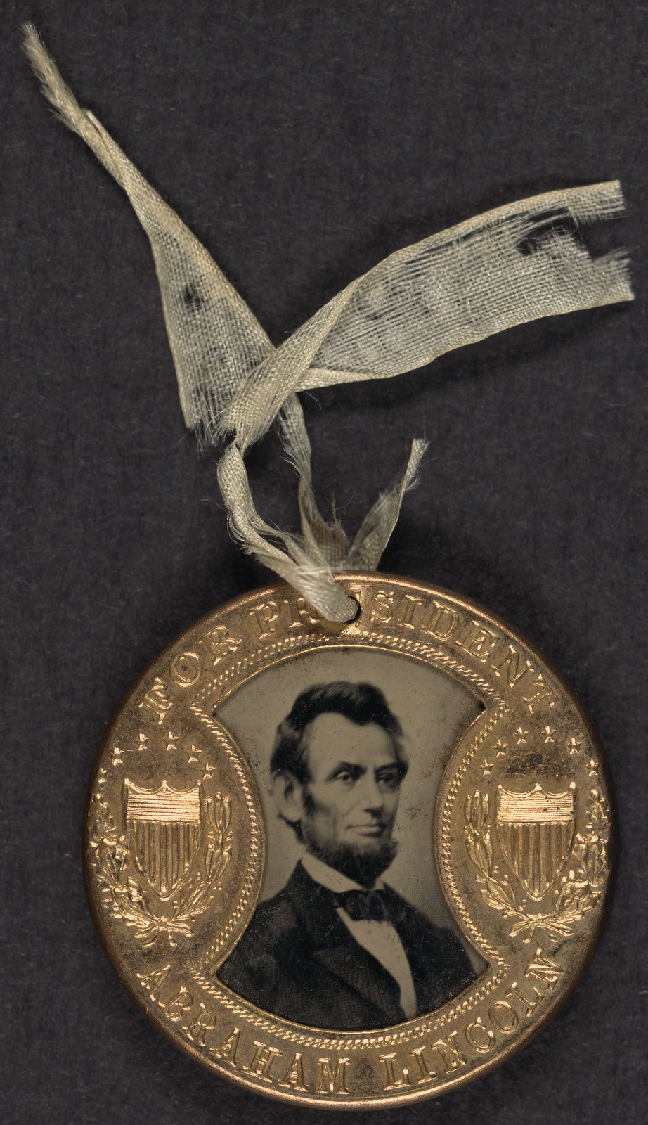 Brass campaign badge reading For President Abraham Lincoln, with portrait — historic image