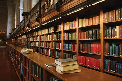 Library interior with wooden bookshelves and stacked books