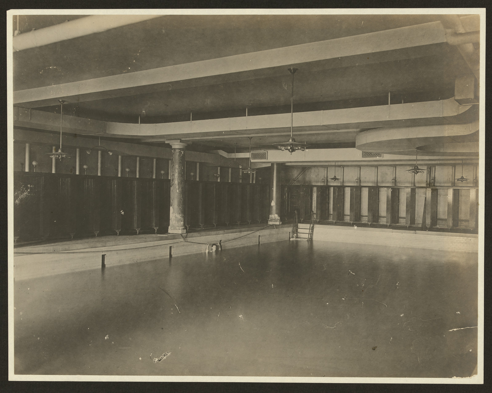 Empty indoor swimming pool with dressing cubicles and columns — historic image