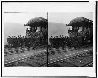 [President Roosevelt, standing with twelve other men on railroad tracks, in front of locomotive]