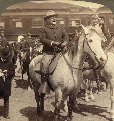 Laughing rider on gray horse beside railway car